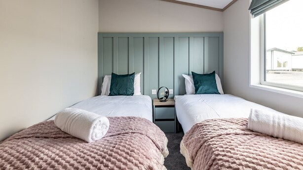 A twin room with two beds, a nightstand, a mirror, and a window with a view. - Lodge No 173 | Stewart's Resort Cameron (Cameron)
