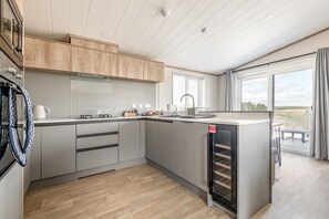 A modern kitchen with wooden cabinets, a built-in oven, and a large window. - Lodge No 173 | Hot Tub | Stewart's Resort Cameron (Cameron)