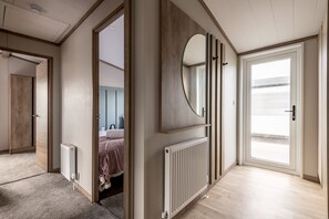 Ein modernes Schlafzimmer mit einem großen Bett, einem begehbaren Kleiderschrank, einem Badezimmer und Blick durch eine Glastür.