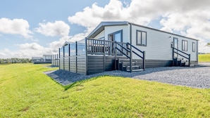 A modern mobile home with a covered porch and a staircase leading to the entrance. - Lodge No 173 | Stewart's Resort Cameron (Cameron)