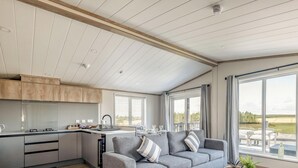 A modern kitchen with a dining area, large windows, and a view of the outdoors. - Lodge No 173 | Stewart's Resort Cameron (Cameron)