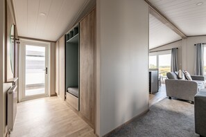 A modern interior with a sliding door leading to a balcony, a built-in bench, and a seating area with a view. - Lodge No 173 | Hot Tub | Stewart's Resort Cameron (Cameron)
