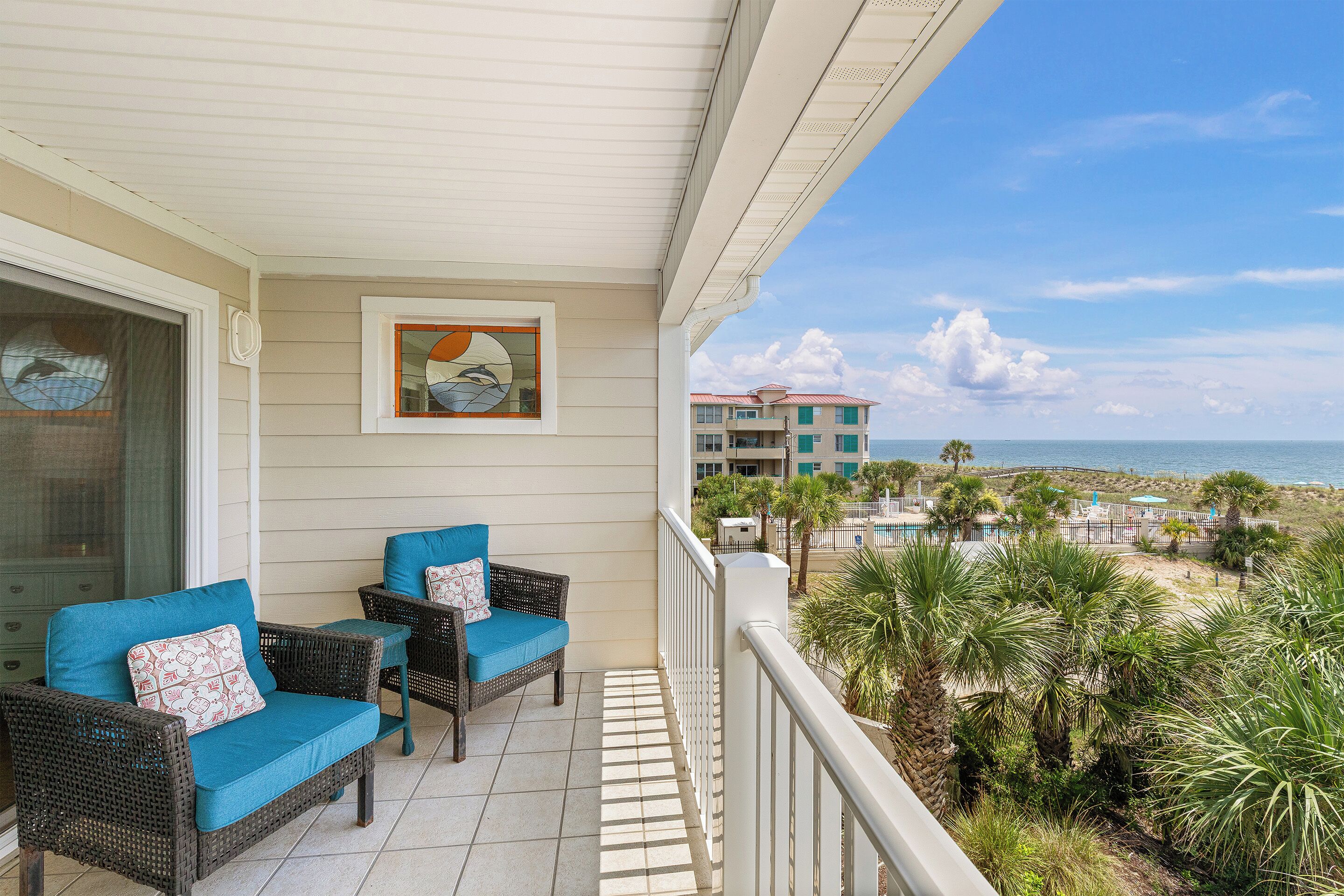 A balcony with wicker furniture and a view of the ocean.