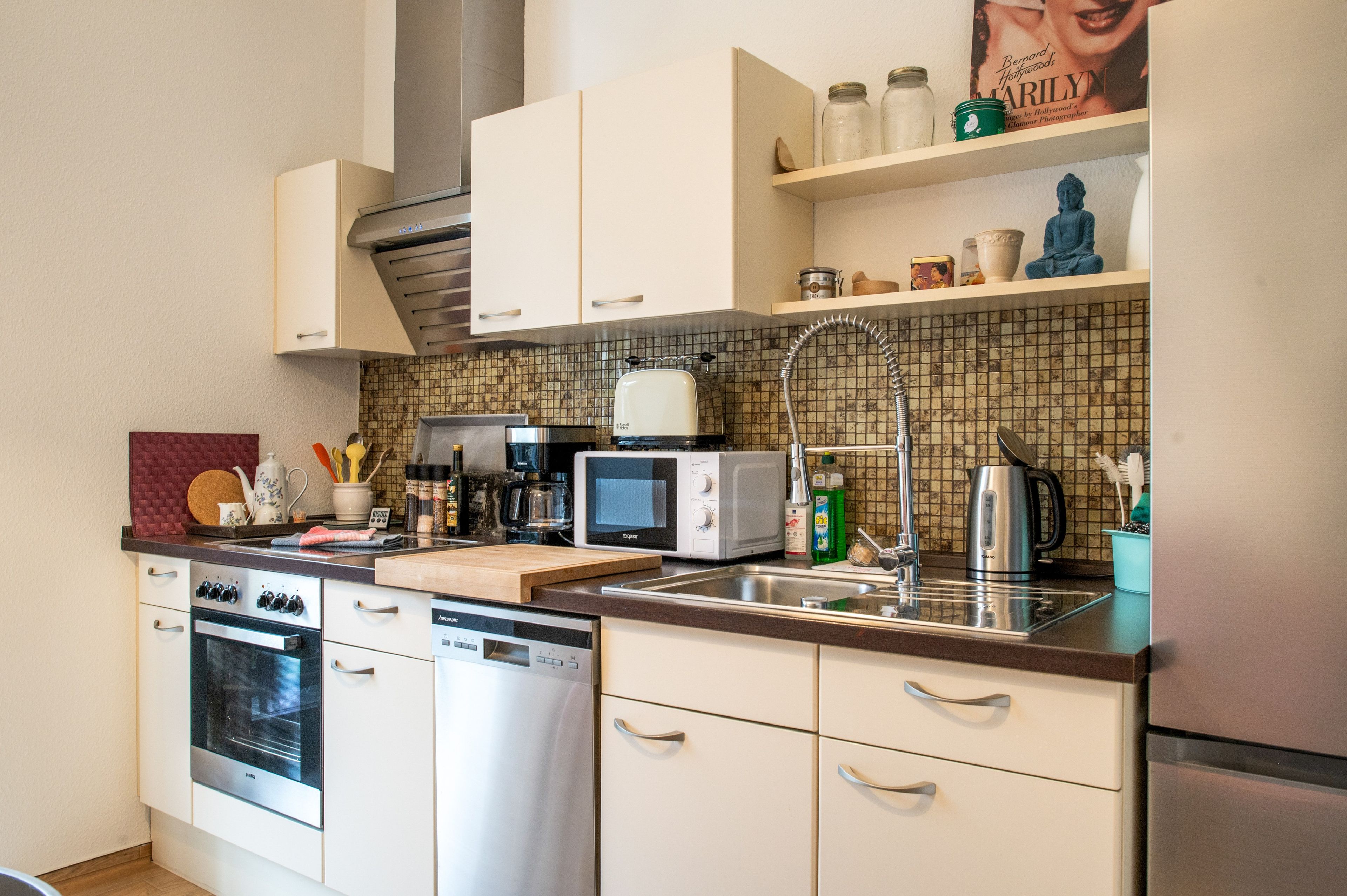 A modern kitchen with stainless steel appliances, a microwave, a toaster, and a kettle.