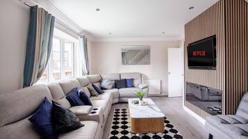 A modern living room with a sectional sofa, a coffee table, a TV, and a patterned rug.