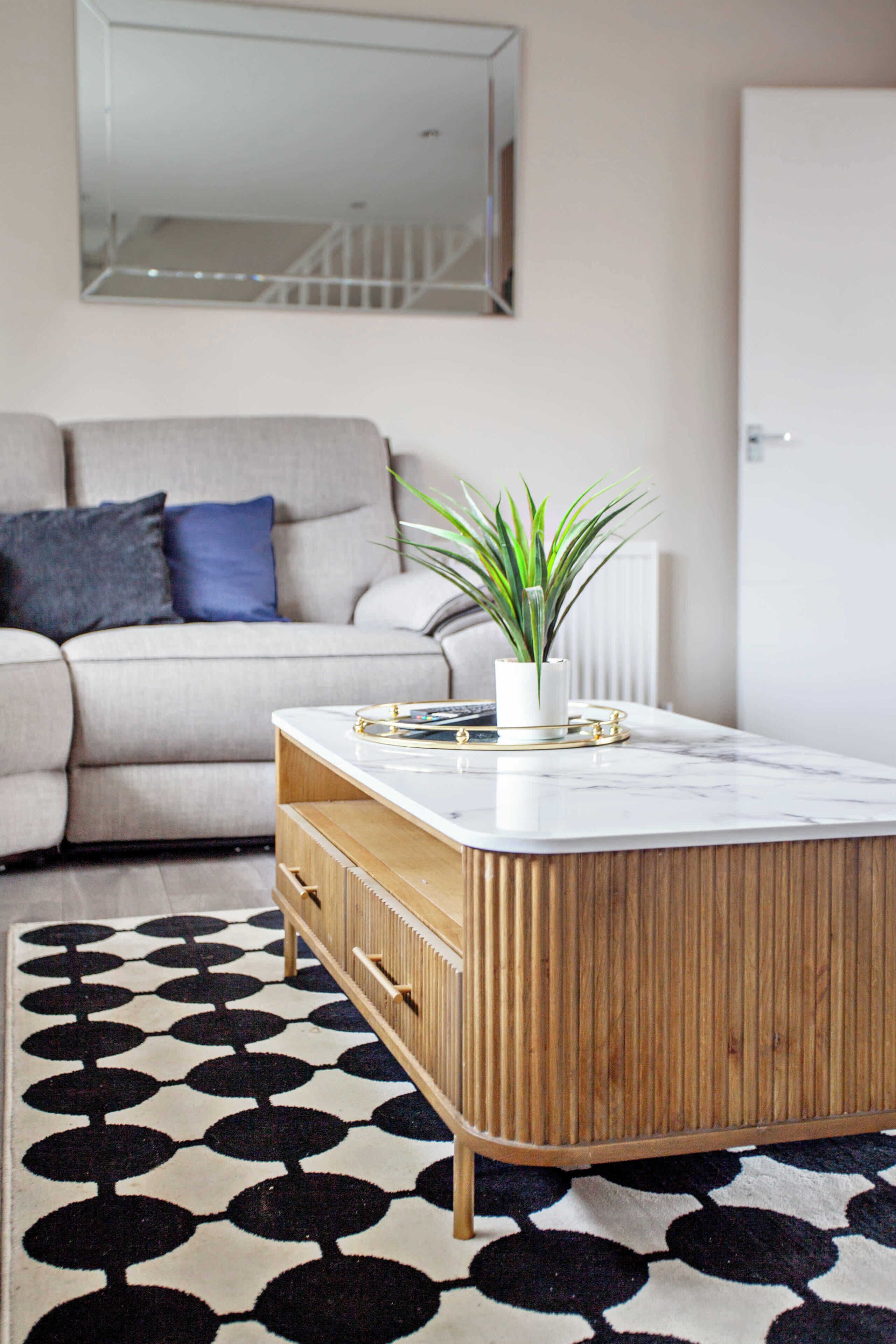 A living room with a sofa, a coffee table, and a patterned rug.