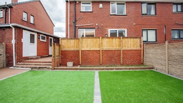 A residential property with a brick house, a wooden fence, and a well-maintained lawn.