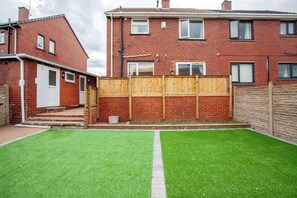 A residential property with a brick house, a wooden fence, and a well-maintained lawn. - Peaceful Countryside Lodge: Scenic Views & (Barnsley)