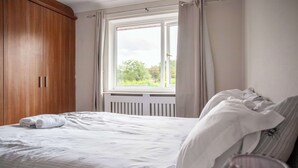 Ein Schlafzimmer mit einem Bett, einem Fenster und einem Holzschrank.