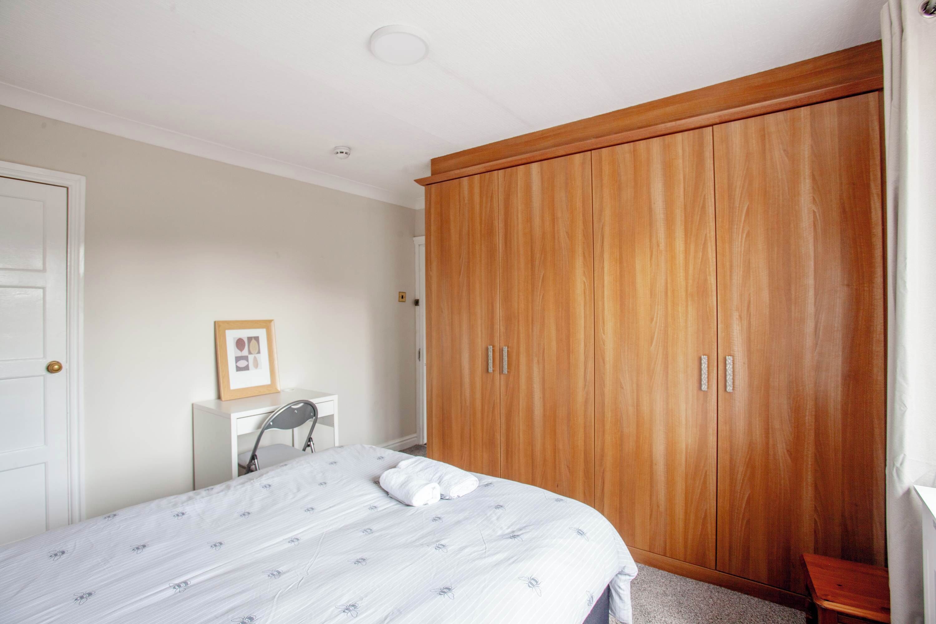 Une chambre à coucher avec un lit, une armoire en bois, un bureau et une chaise.