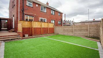 A residential property with a fenced backyard, a brick house, and a well-maintained lawn.