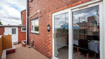 A brick house with a sliding glass door leading to a patio with a table and chairs.