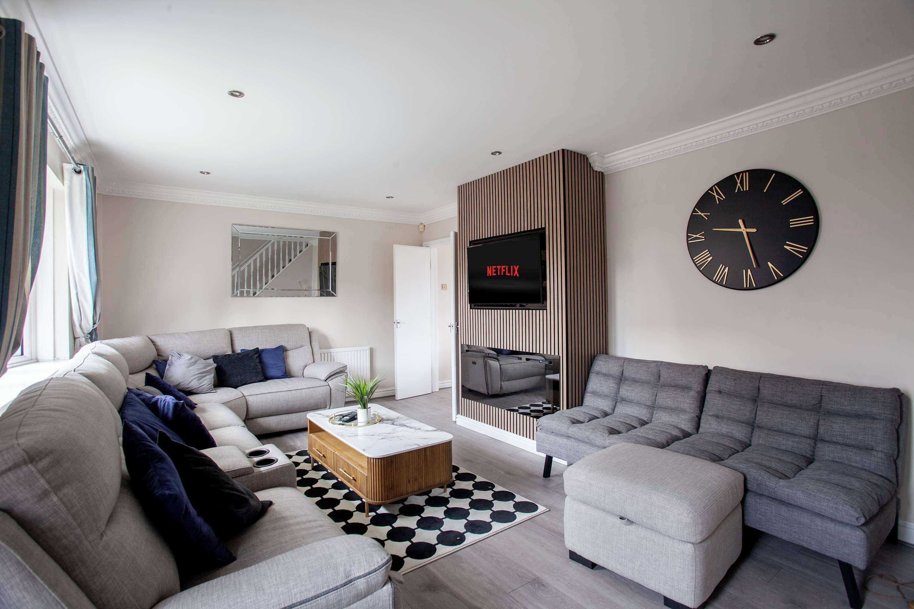 Una sala moderna con un sofá modular, una mesa de centro y un gran reloj de pared.