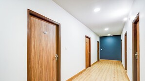 A corridor with wooden doors and a blue wall at the end. - Collection O GNRC Hospital Dispur (Guwahati)