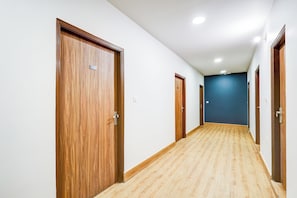 Ein Korridor mit Holztüren und einer blauen Wand am Ende.