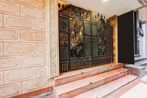 Un conjunto de puertas de metal negro ornamentadas, con diseños intrincados, que conducen a una escalinata de mármol.