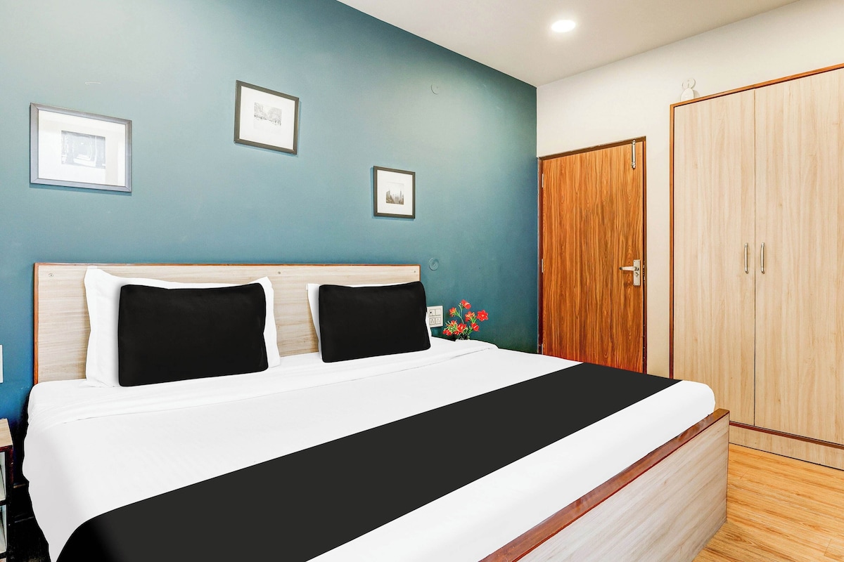 Ein Hotelzimmer mit einem großen Bett, zwei schwarzen Kissen, einem Holzschrank und zwei gerahmten Bildern an der Wand.