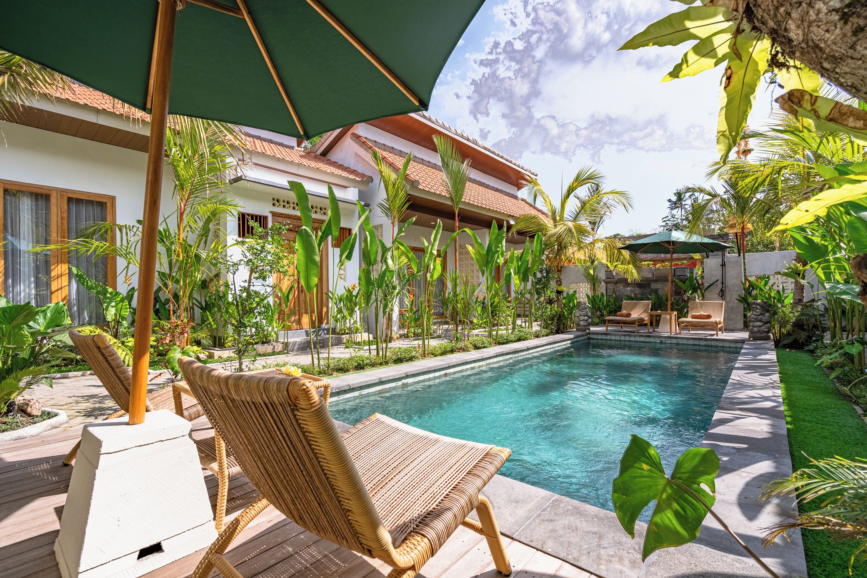 A poolside area with a lounge chair, a small pool, and tropical plants.