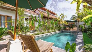 A poolside area with a lounge chair, a small pool, and tropical plants.