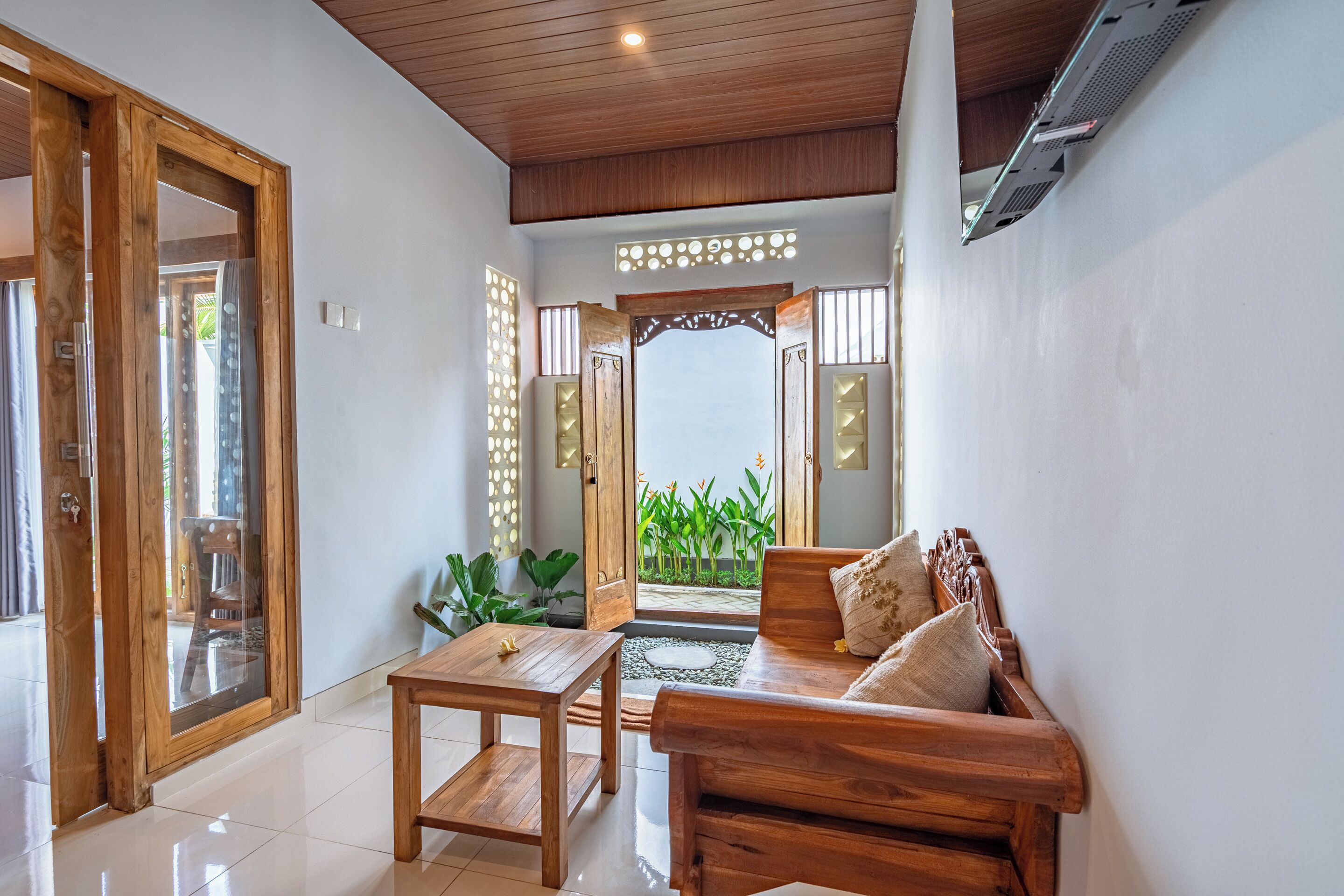 Un interior de madera con sofá, mesa y vistas a un jardín.