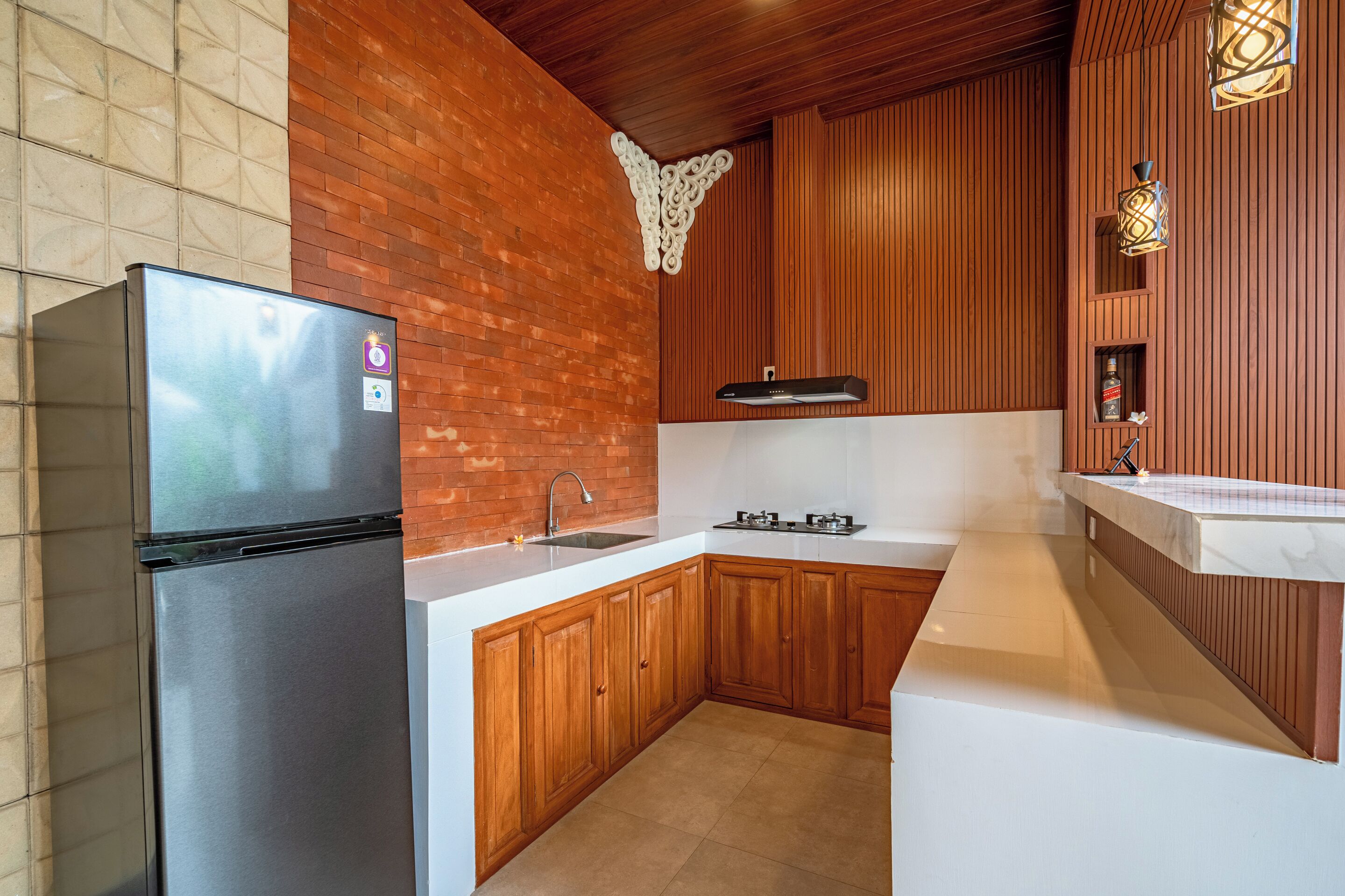 A kitchen with a stainless steel refrigerator, wooden cabinets, a white countertop, and a built-in stove.