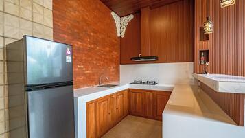 A kitchen with a stainless steel refrigerator, wooden cabinets, a white countertop, and a built-in stove.