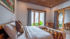 Ein Schlafzimmer mit einem großen Bett, einem Schreibtisch und Blick auf Grün.