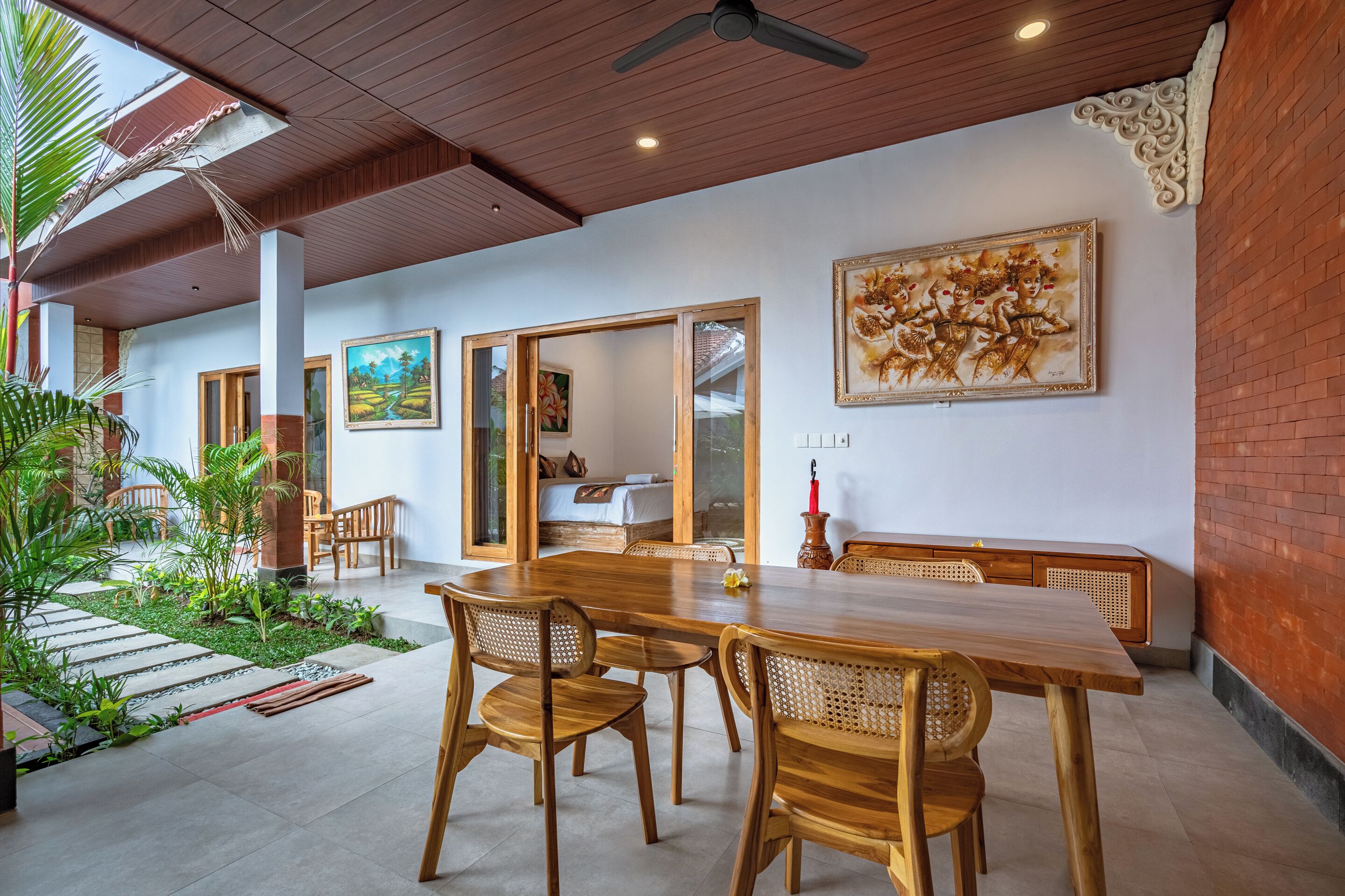 Un comedor espacioso con una mesa y sillas de madera, vista al jardín y un cuadro en la pared.