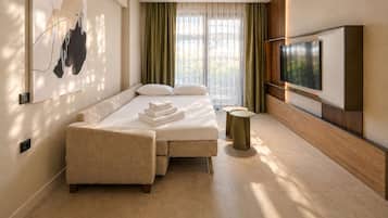 Een moderne hotelkamer met een bed, een bank, een televisie en een schilderij aan de muur.