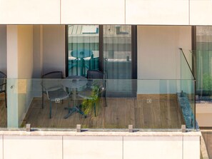 A modern outdoor seating area with a glass balustrade, a round table, and four chairs.