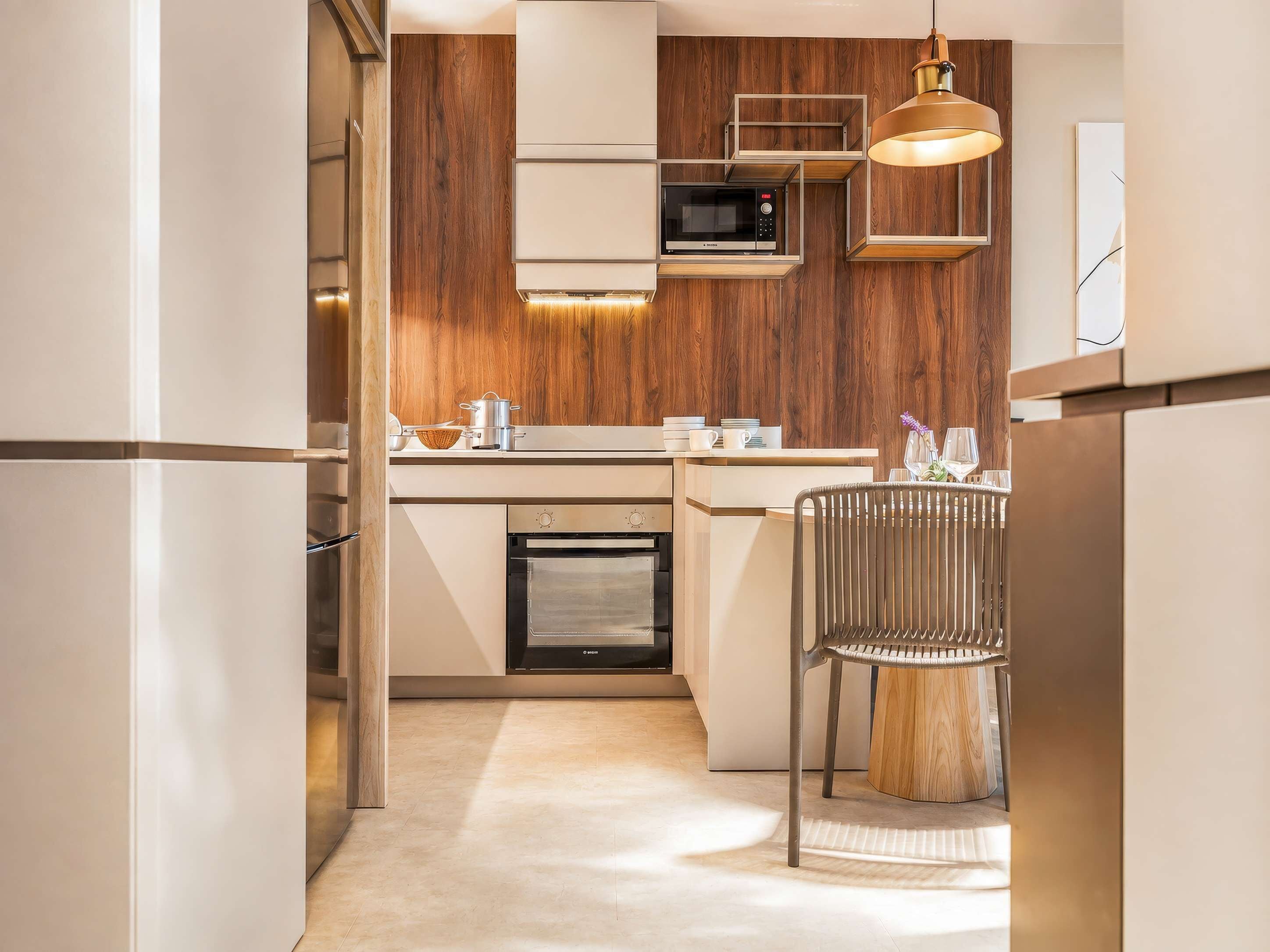 Una cocina moderna con horno empotrado, microondas y una pared de acento de madera.