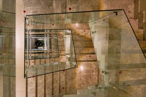 A glass-walled staircase with a marble floor, leading to a lower level. - Khora Suites (Antalya)