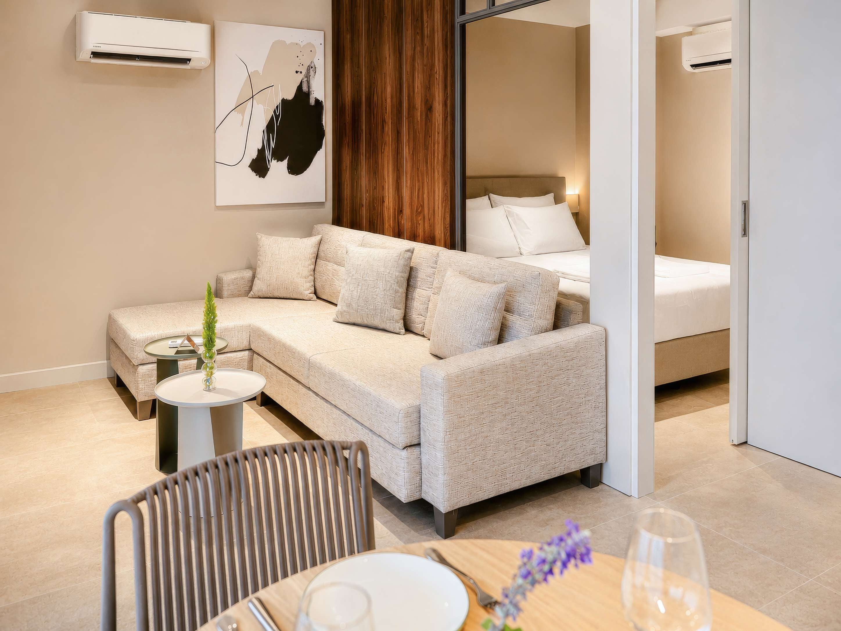 Un salon moderne avec un canapé, une table à manger et des chaises, et un lit en arrière-plan.