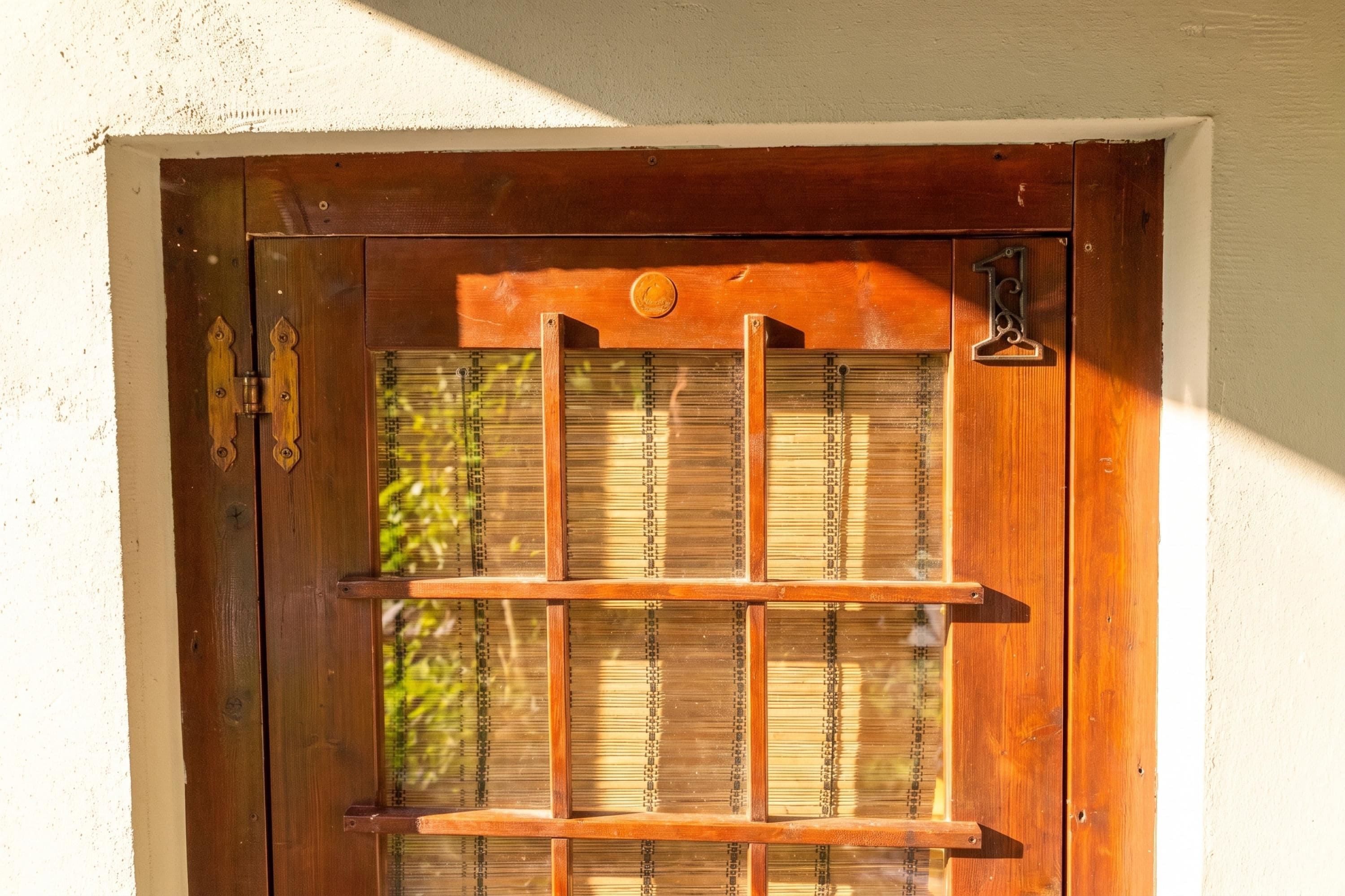 Una puerta de madera con una placa de número y una ventana con persianas.