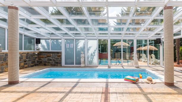 An indoor swimming pool with a glass ceiling, stone pillars, and a view of the outside. - Paradise Forest Glamping Rooms (Koper)