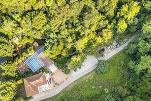 An aerial view of a property with a swimming pool, a covered patio, and a road with parked cars. - Paradise Forest Glamping Rooms (Koper)