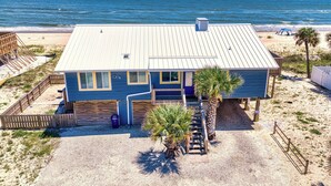 Ein Strandhaus mit Metalldach, großen Fenstern und einer kleinen Veranda.