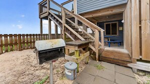 Eine Holzterrasse mit Grill und Mülleimer.