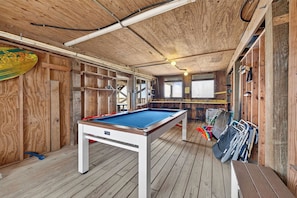 Ein Billardtisch in einem Holzraum mit schrägem Dach und Holzwänden.