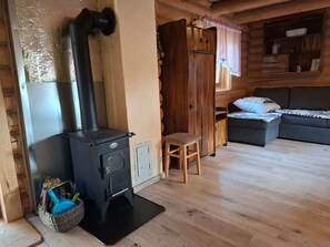 Un accogliente interno di una baita con un camino a legna, un divano e un piccolo tavolo.