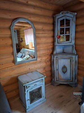 Una stanza rustica in legno con uno specchio, un armadietto e un tavolino.