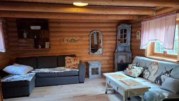 Interior acollidor d'una cabana amb un sofà, una taula petita i un armari.