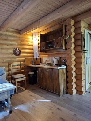 A cozy cabin interior with a wooden interior, a kitchen area with basic appliances, a dining table with chairs, and a small seating area. - Cosy Cottage — Agrotourism Jizerska Zagroda (Gierczyn)