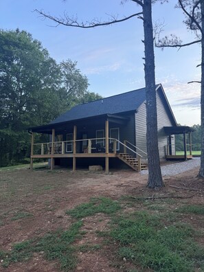 A cabin with a wooden deck, a covered porch, and a staircase leading to the entrance.