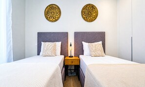 Ein Doppelzimmer mit zwei Betten, einem Nachttisch, einer Lampe und zwei Wandbildern.