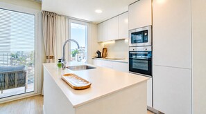 A modern kitchen with a large island, built-in oven, and a view to the outside. - Unic Serenity Apartment Javea (Javea)