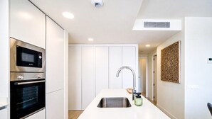 A modern kitchen with a built-in oven, microwave, and a large island with a sink. - Unic Serenity Apartment Javea (Javea)