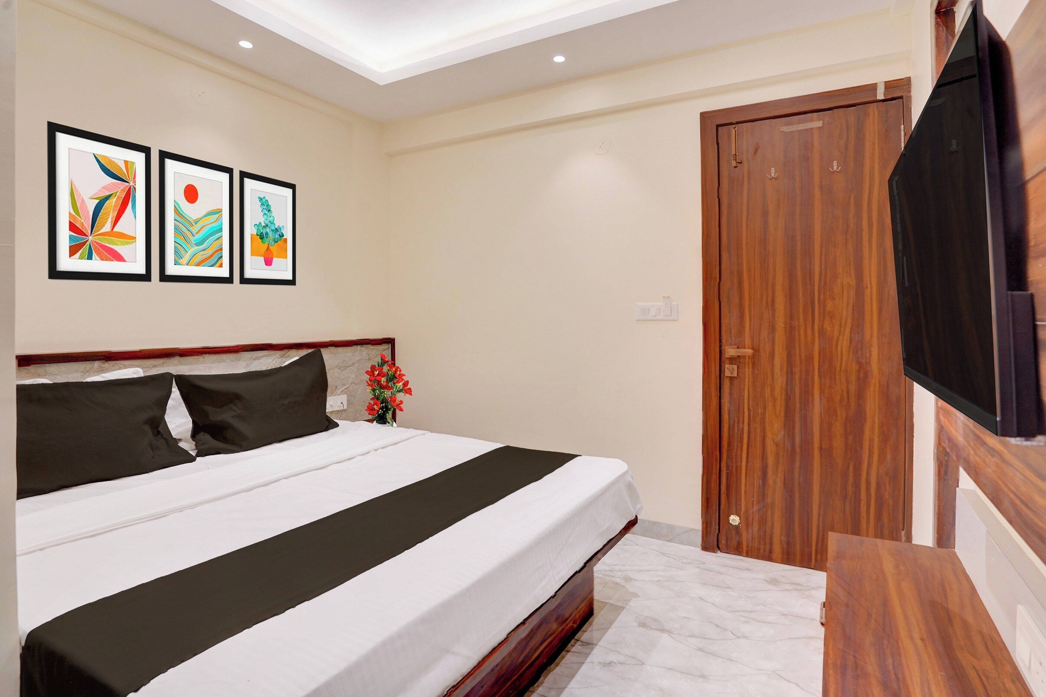 Ein Hotelzimmer mit einem Bett, einem Fernseher und drei gerahmten Kunstwerken an der Wand.