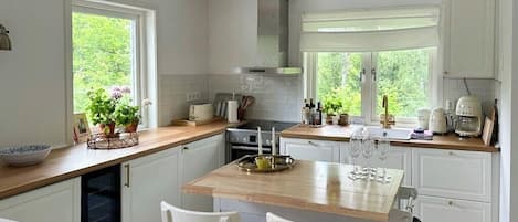 A kitchen with white cabinetry, a wooden countertop, and a central island with seating.
