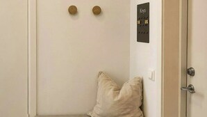 Een kamer met een bankje, sleutels aan de muur en een deur.